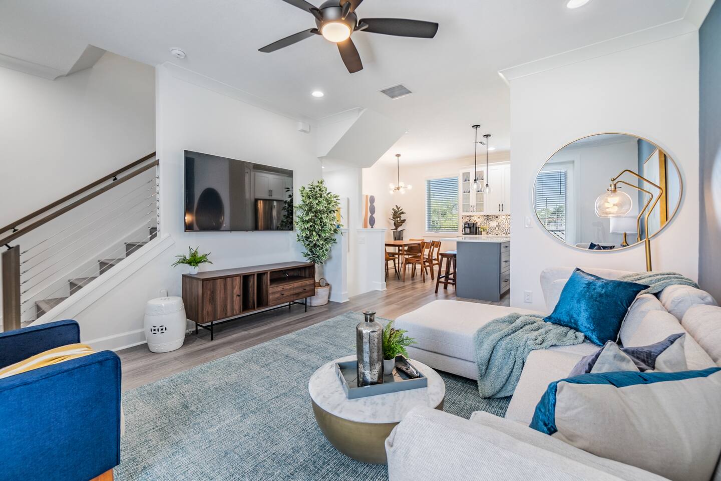 Tampa Oasis bright living room with blue accents, a sofa and open kitchen