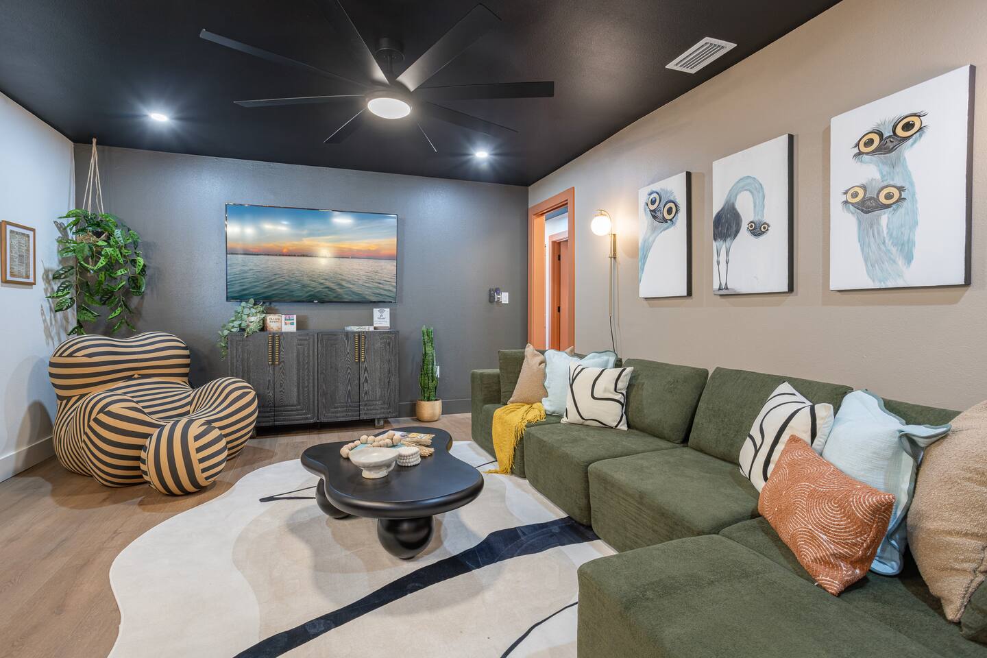 Attitude & Altitude living room with a green sectional, striped armchair and owl artwork