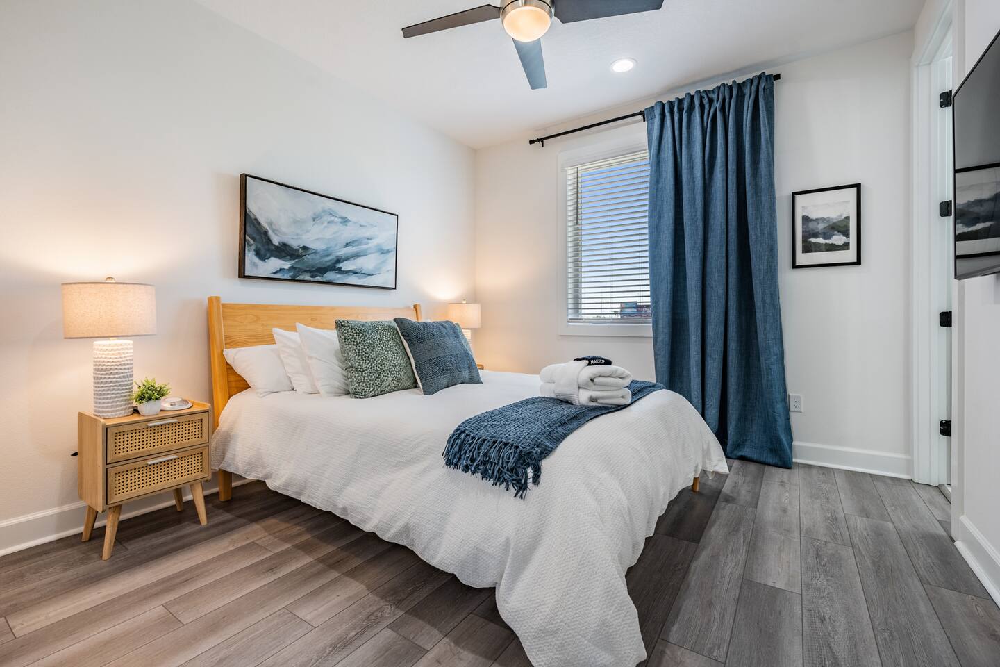 Tampa Oasis bedroom with a wooden bed frame, white bedding and blue curtains